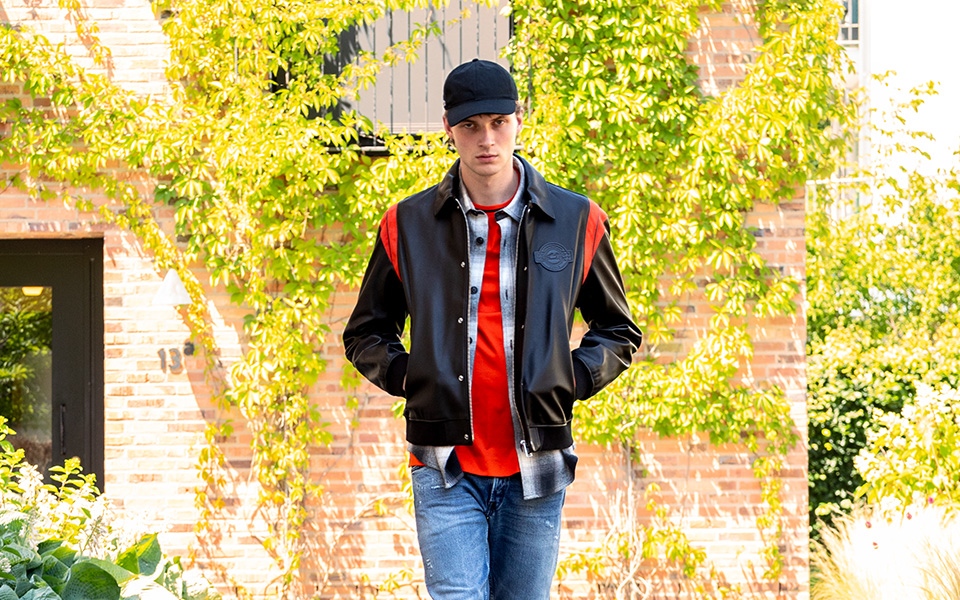 Schwarze Lederjacke mit roten Details, kombiniert mit Jeans und Sneakern für sportlichen Streetstyle.