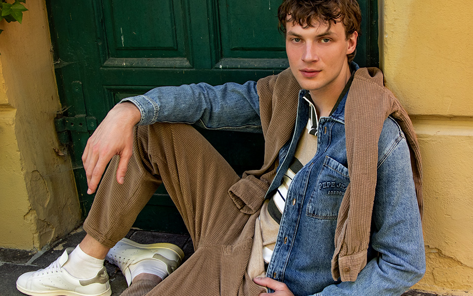 Jeansjacke im Vintage-Look, kombiniert mit Cordhose und weißen Sneakern, lässiger Casual-Style.