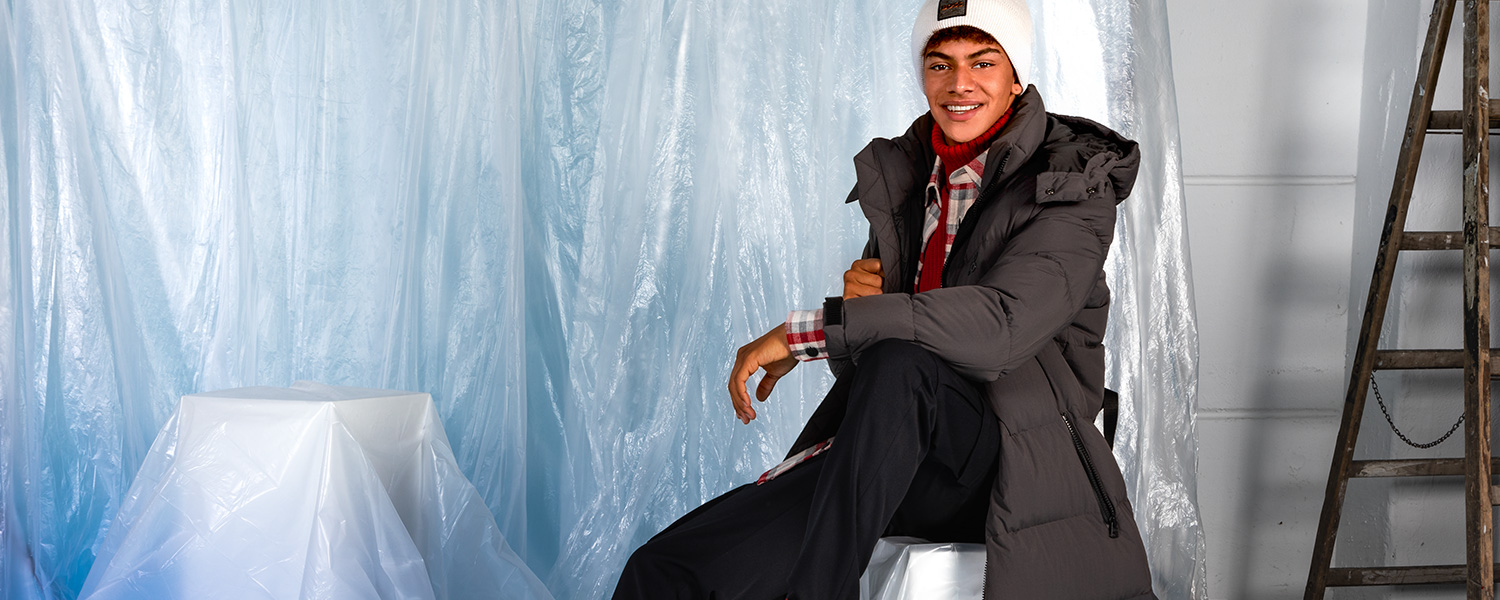 Warmer Wintermantel in Dunkelgrau – lässig gestylt mit Karobluse, Mütze und Schal.