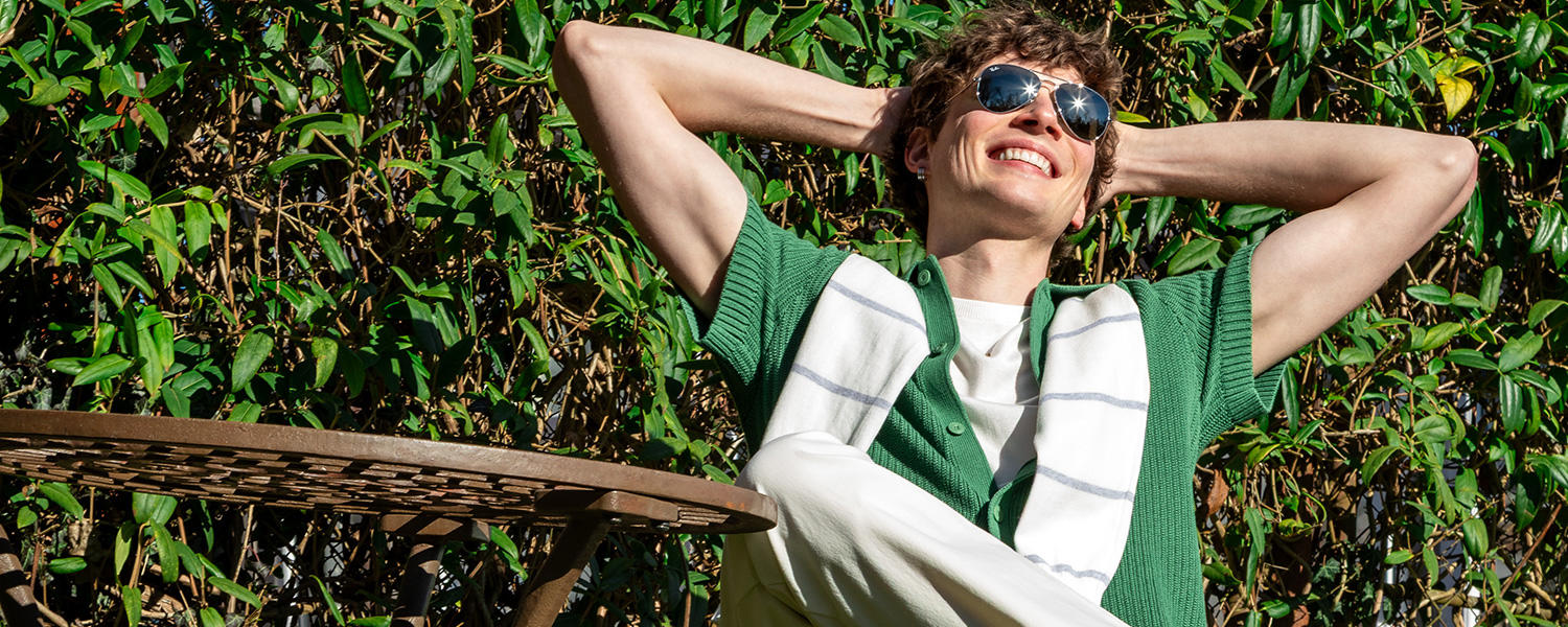 Mann in grünem Strickshirt mit Sonnenbrille – entspannter Sommermoment im lässigen Casual-Look.