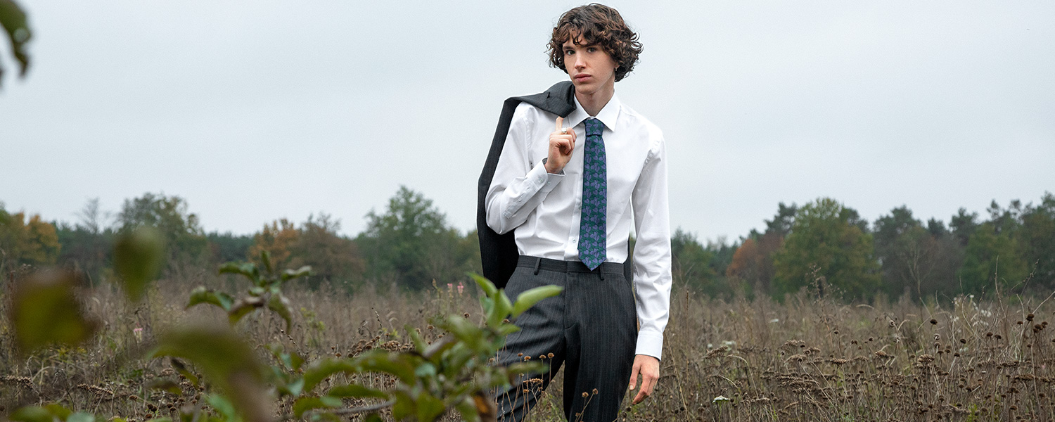 Weißes Hemd mit gemusterter Krawatte – smarter Business-Look mit Sakko über der Schulter.