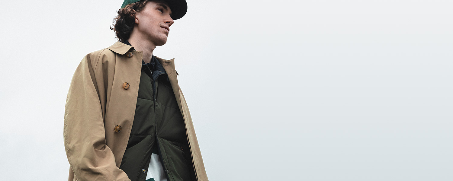 Klassischer Trenchcoat in Beige – kombiniert mit sportivem Layering und Cap.