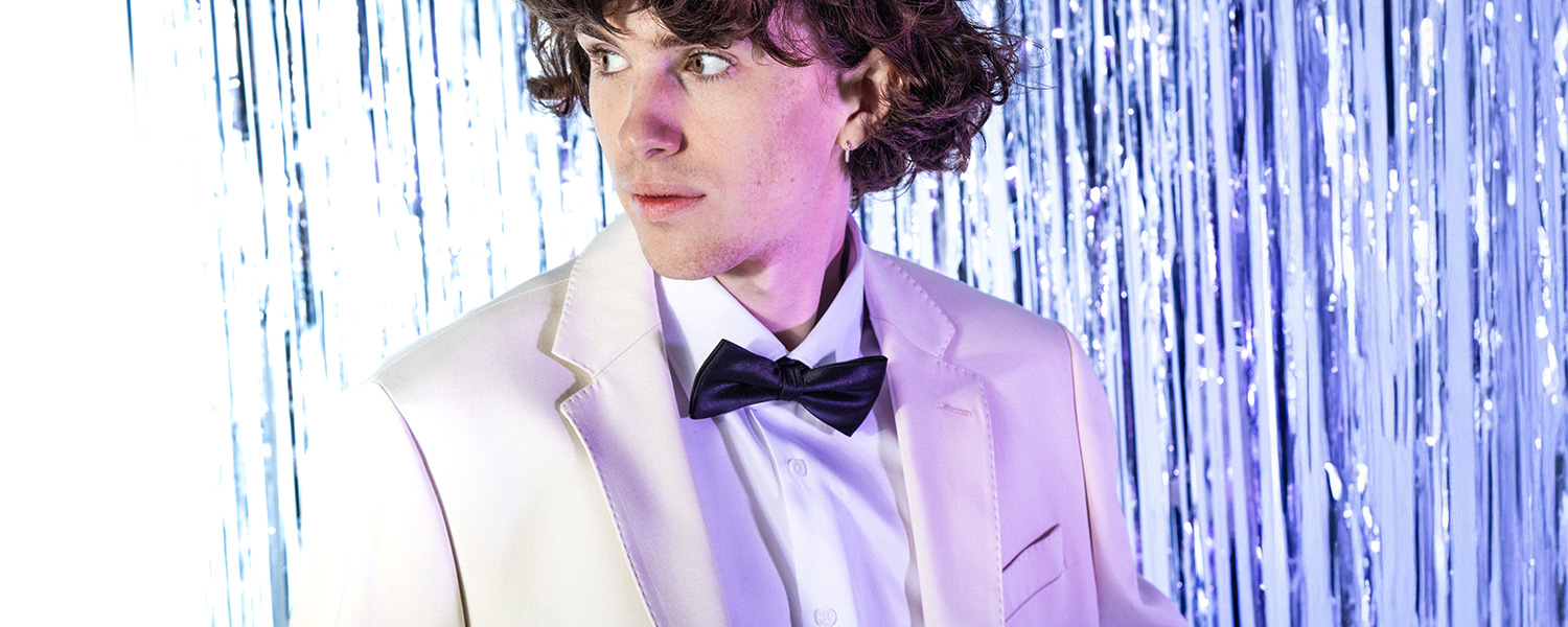 Weißer Smoking mit schwarzer Fliege – eleganter Look für festliche Anlässe mit modernem Retro-Vibe.