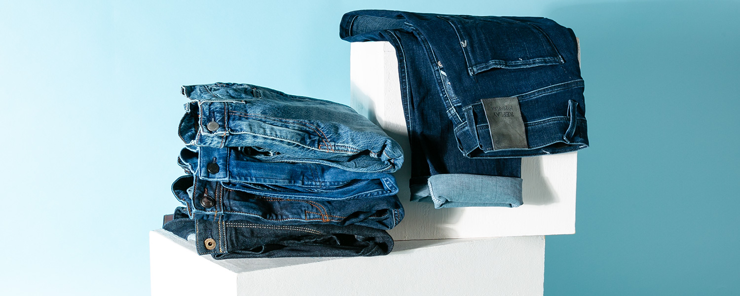 Gestapelte Jeans in verschiedenen Blautönen – moderner Denim-Look mit gepflegter Waschungsvielfalt.