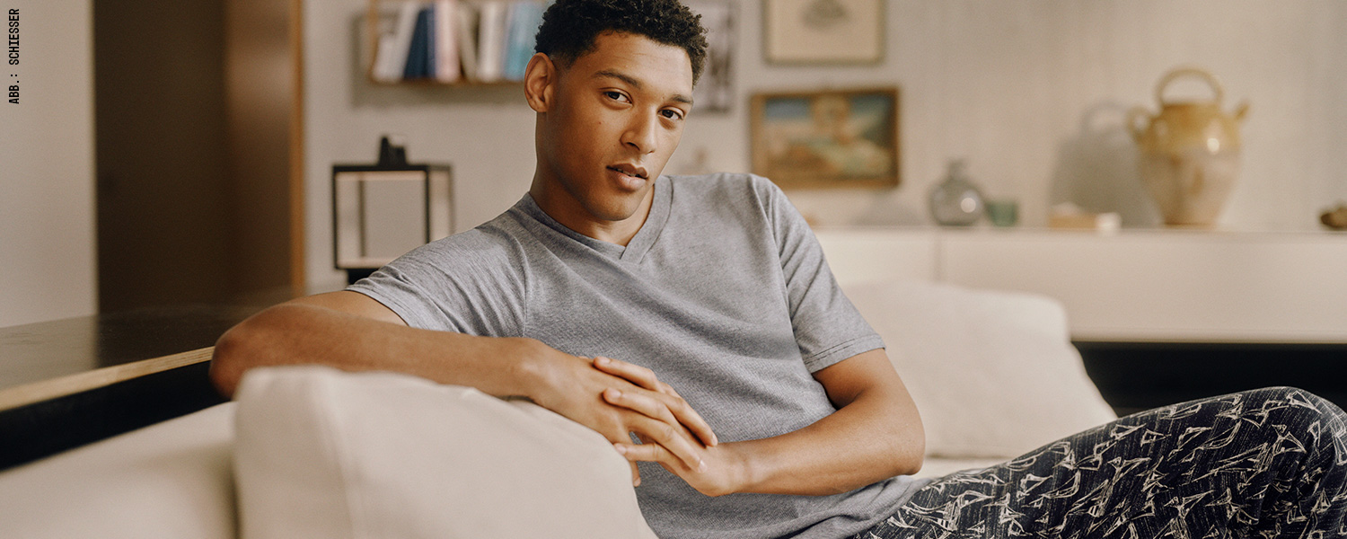 Graues Kurzarm-T-Shirt mit V-Ausschnitt, kombiniert mit gemusterter Hose – entspannter Freizeitstyle.