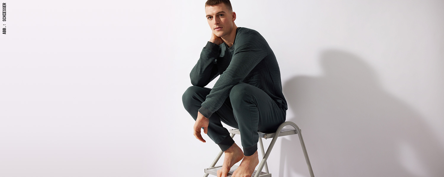 Mann in dunkelgrünem Longsleeve und passender Hose, gemütlicher Loungewear-Look.