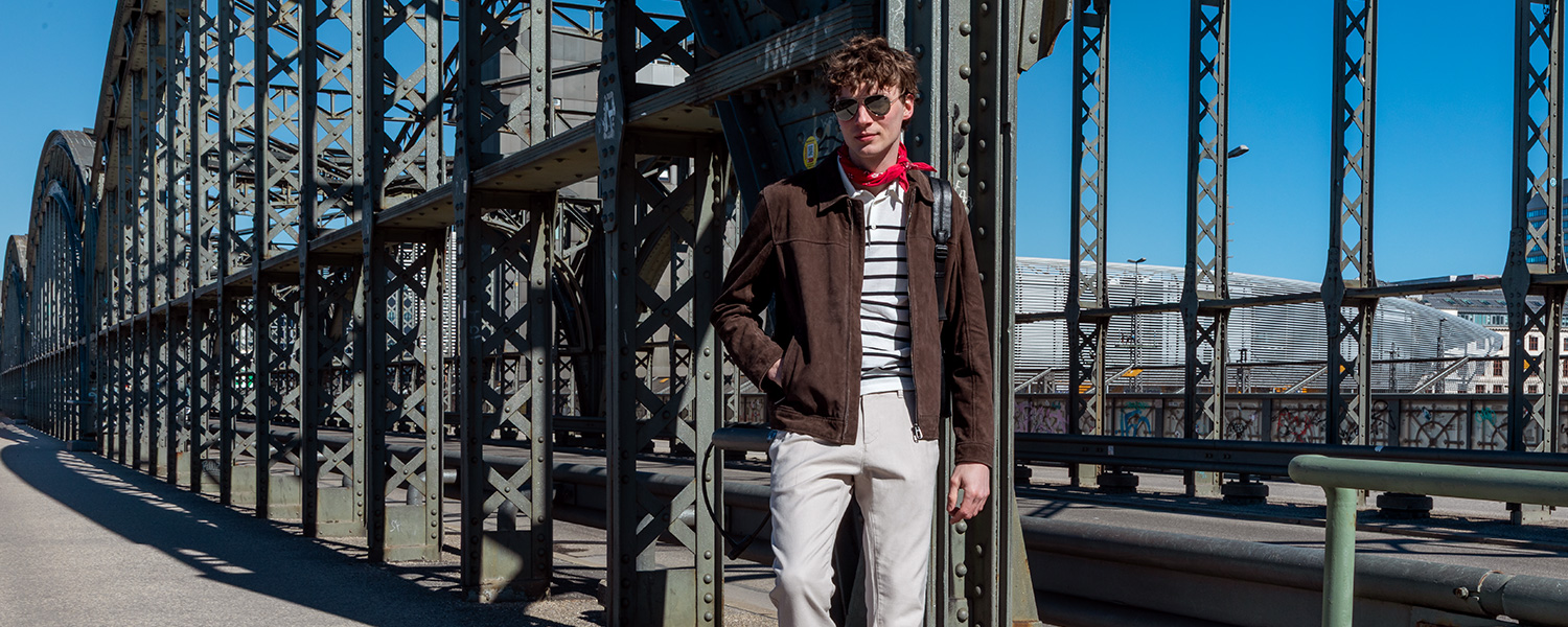 Gestreiftes Poloshirt mit brauner Wildlederjacke – lässiger City-Look mit französischem Flair.