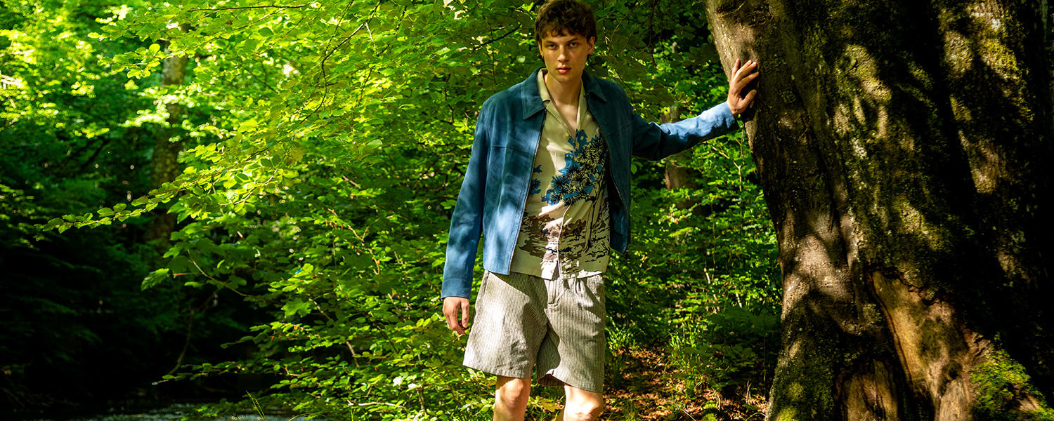 Gemusterte Shorts mit blauer Jacke – entspannter Sommer-Look im Naturstil.