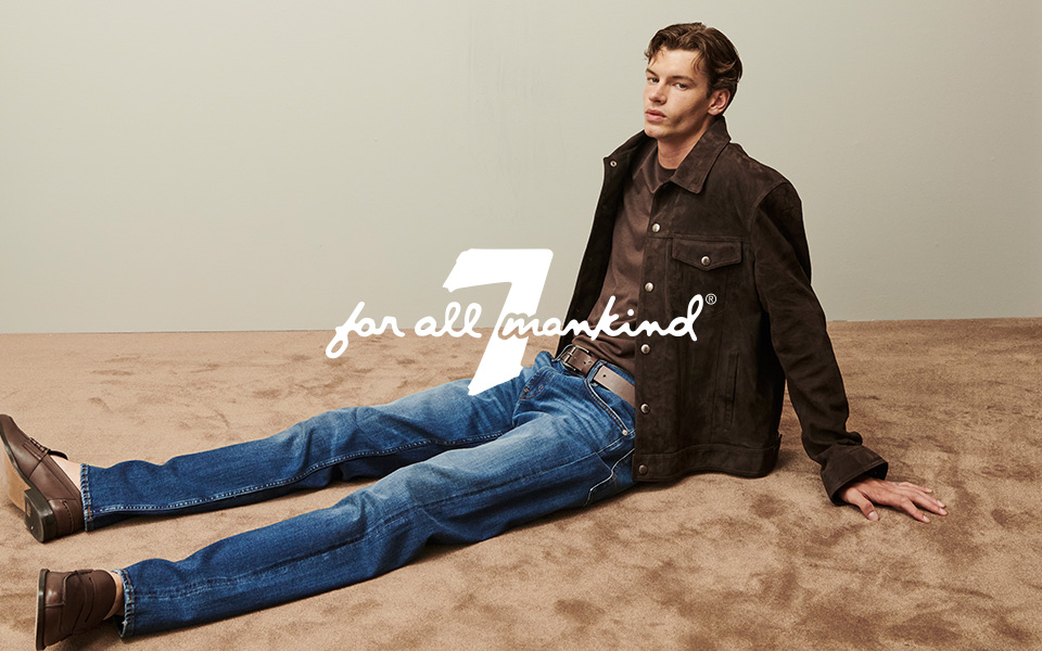 Mann in brauner Wildlederjacke und blauer Jeans, lässig sitzend auf Teppichboden