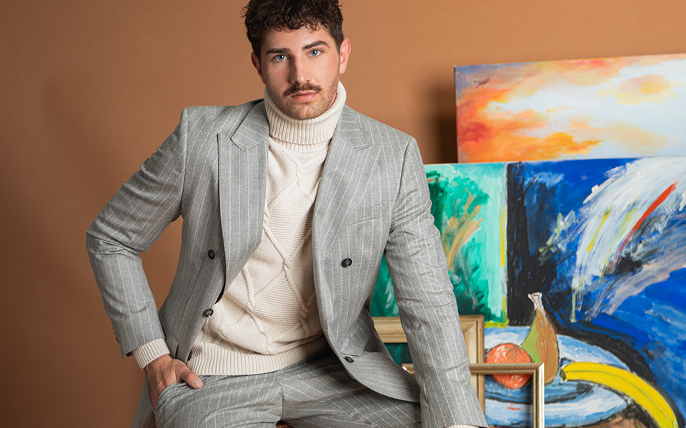 Grau gestreifter Anzug mit cremefarbenem Rollkragenpullover, leger präsentiert vor Kunstwerken