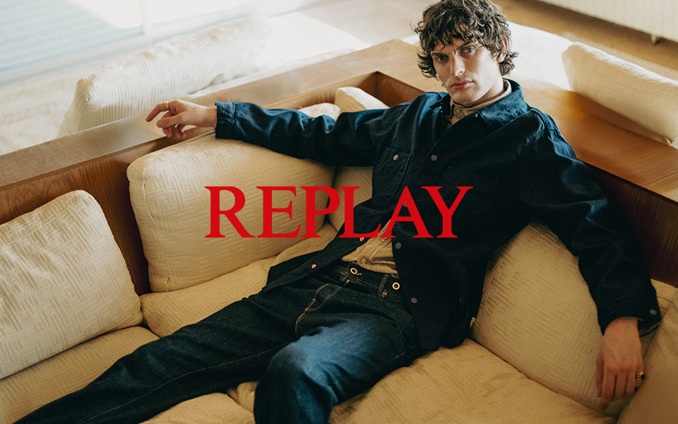 Mann in dunkelblauem Denim-Hemd und Jeans lässig auf einem Sofa sitzend