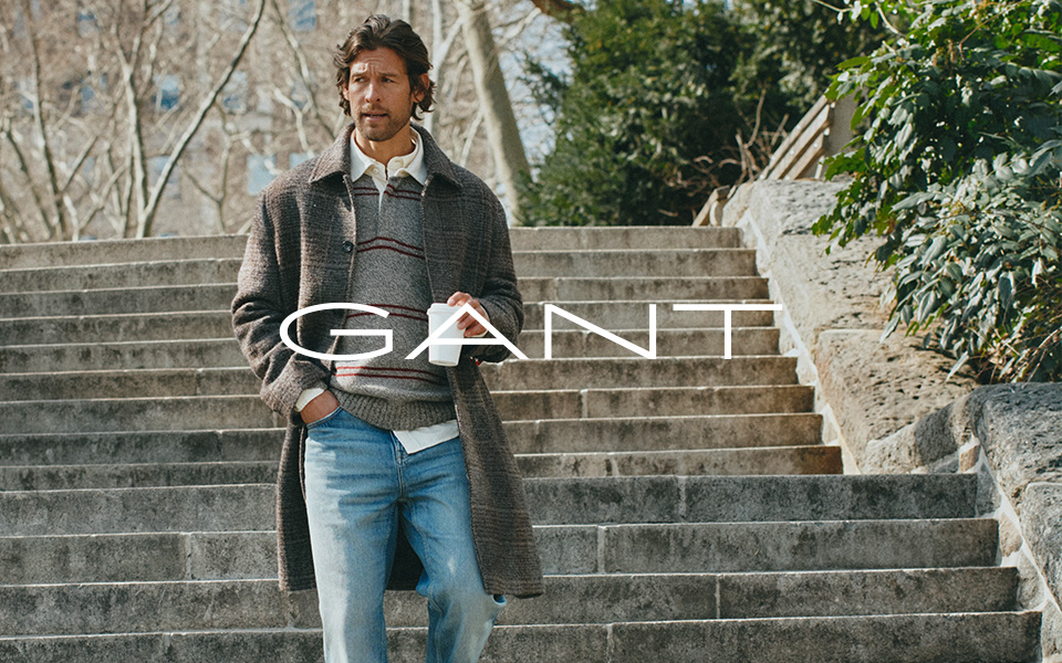 Mann in grauem Wollmantel mit gestreiftem Pullover und Jeans, Treppe hinabgehend