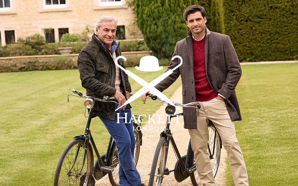 Männer in braunen Blazern und Pullovern mit Fahrrädern im Garten, herbstlich gekleidet