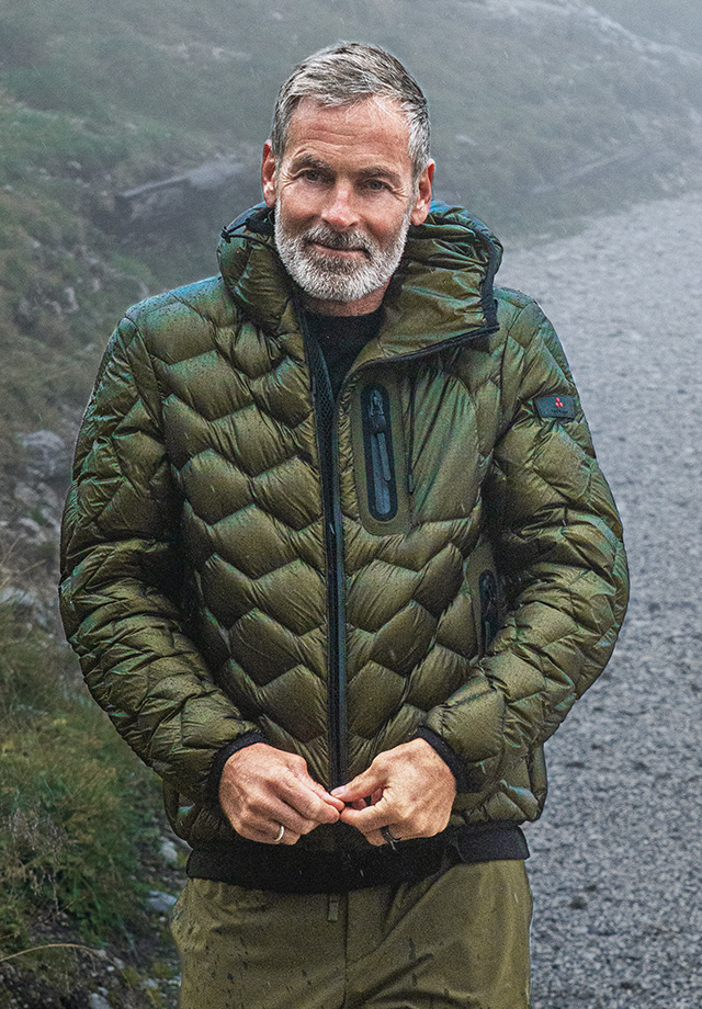 Mann in olivgrüner Steppjacke aus Daunenmaterial, outdoor getragen