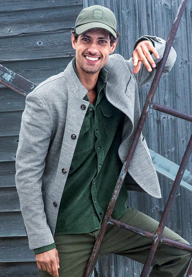 Herren-Sakko in Grau, grüne Cordjacke darunter, legerer Look mit Kappe im Freien