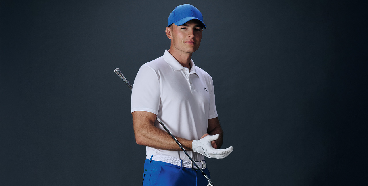 Mann in weißem Poloshirt mit blauer Schirmmütze und Golfschläger, sportlich-lässig präsentiert