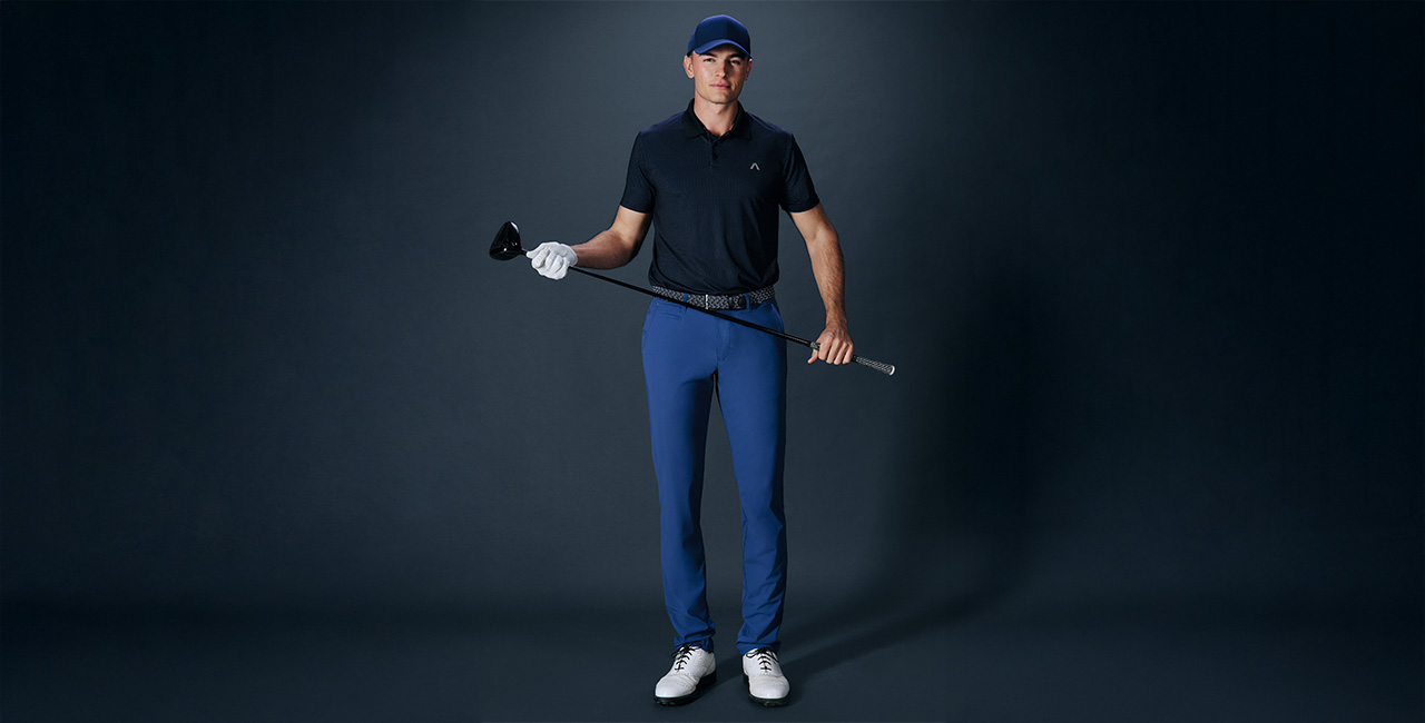 Mann in marineblauem Poloshirt und blauen Golfhosen mit Golfschläger