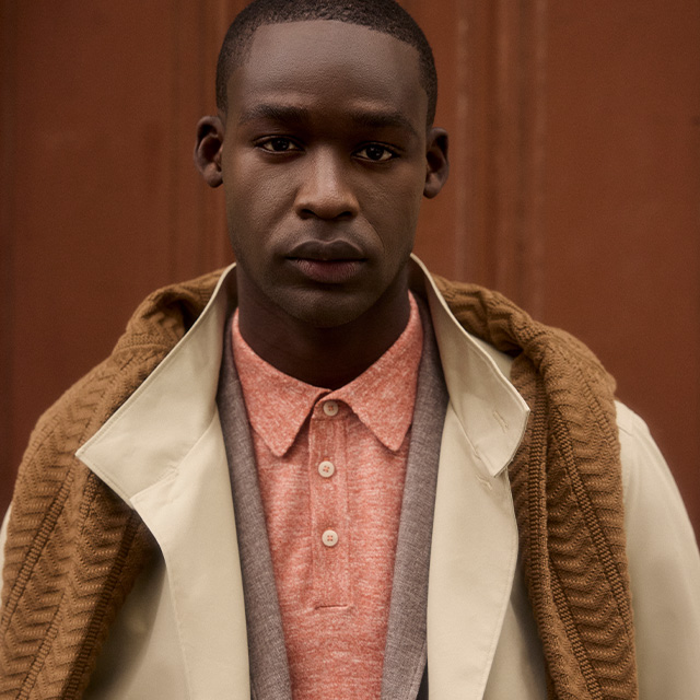 Elegantes rotes Poloshirt aus Baumwolle unter beige Mantel mit braunem Strickpullover, lässig getragen