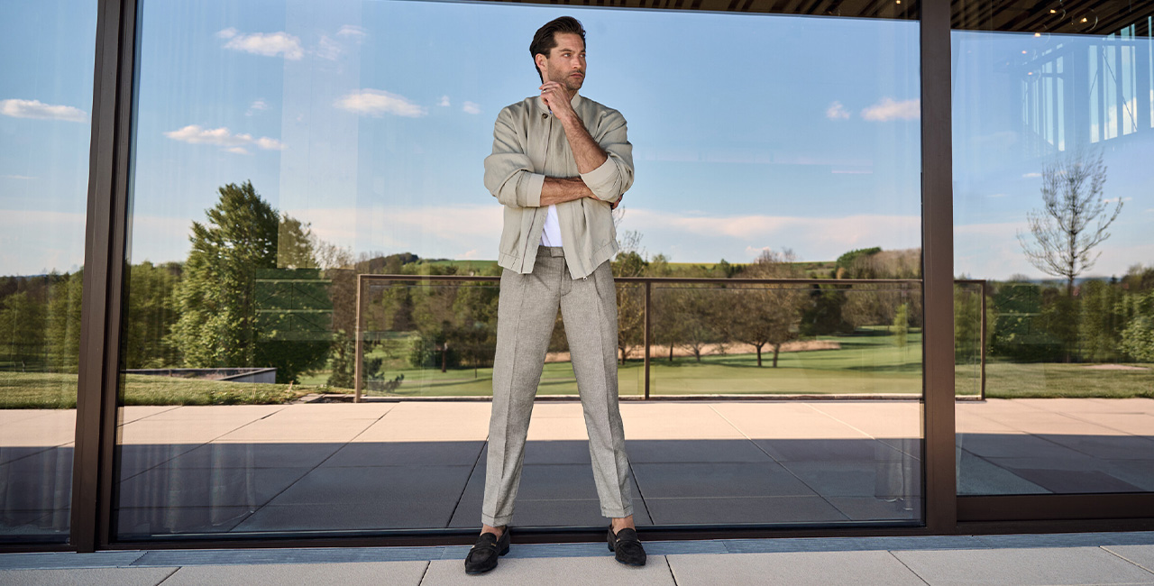 Hellgraue Bügelfaltenhose mit offenem, lässigem Blouson und weißen Shirt, lässig im Freien getragen