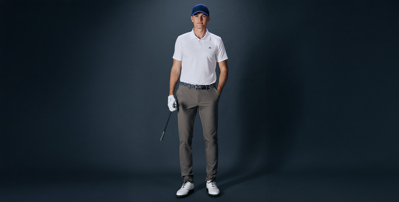 Weißes Poloshirt und graubraune Golfhose, Golfspieler mit blauer Cap, weißen Polo und Golf Schläger, sportlich-elegant gekleidet