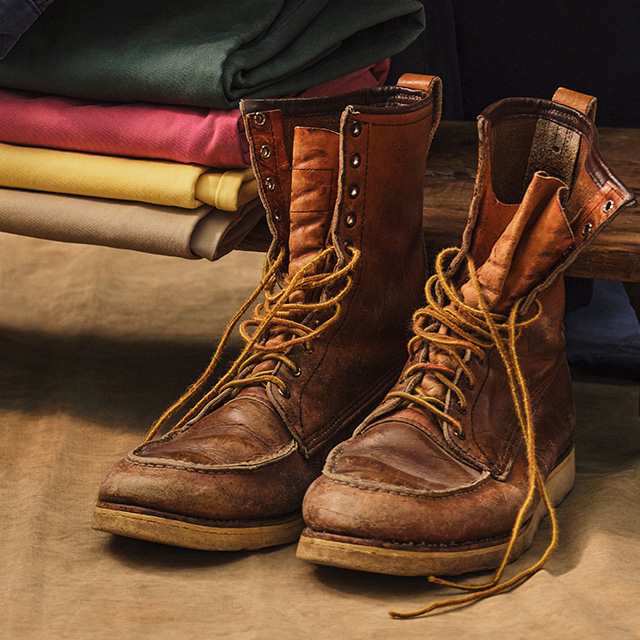 Braune Lederstiefel mit Schnürsenkeln, lässig neben gefalteten Stoffen platziert