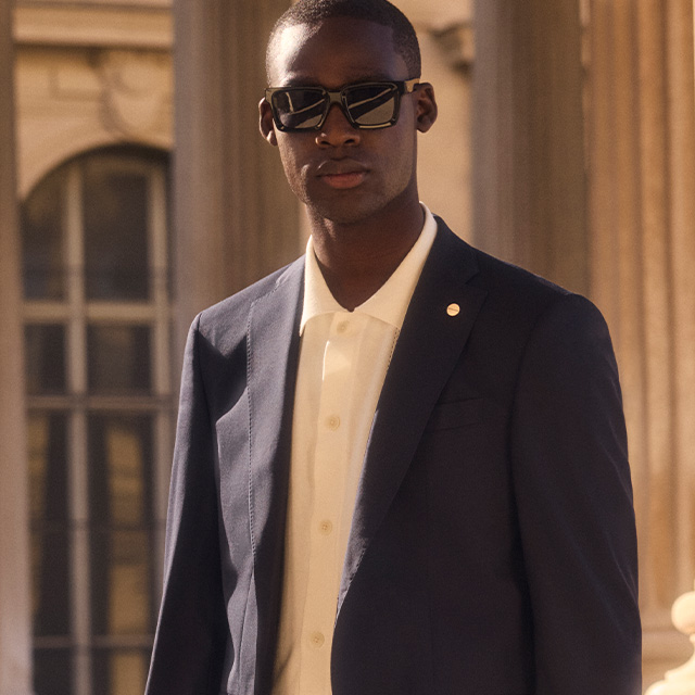 Mann in dunkelblauem Blazer und weißem Poloshirt, klassisch elegant gekleidet