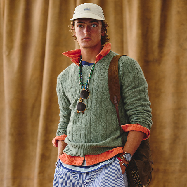 Grüner Strickpullover über orangem Hemd, casual getragen mit Basecap