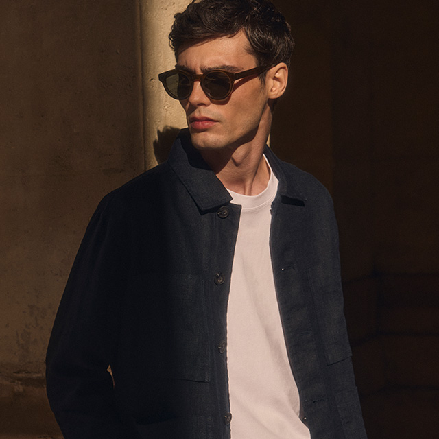 Mann in dunkelblauer Jacke mit weißem T-Shirt bei Sonnenlicht