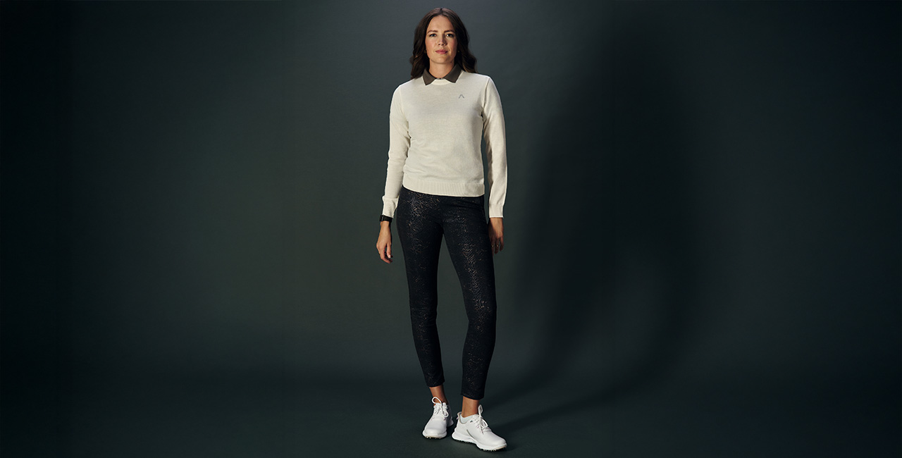 Frau in beigen Pullover, darunter ein graues Polo-Shirt und Jersey Golf Hose mit leichter Musterung von Alberto.