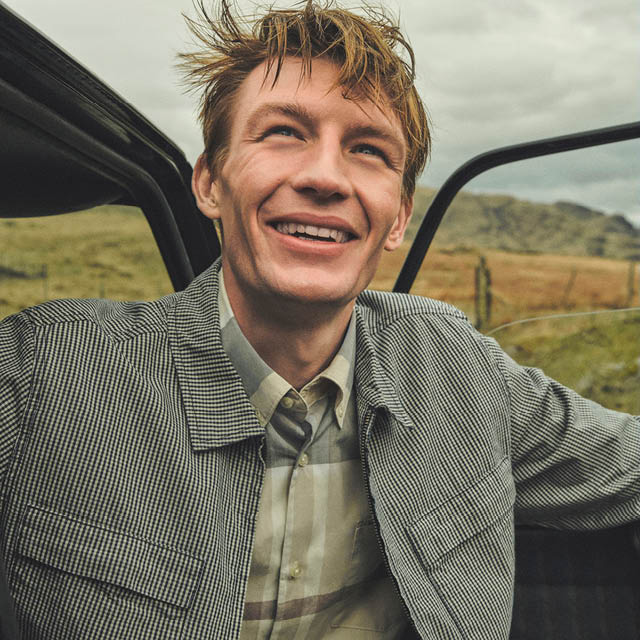 Mann in karierter Jacke und Hemd, lässig im Freien