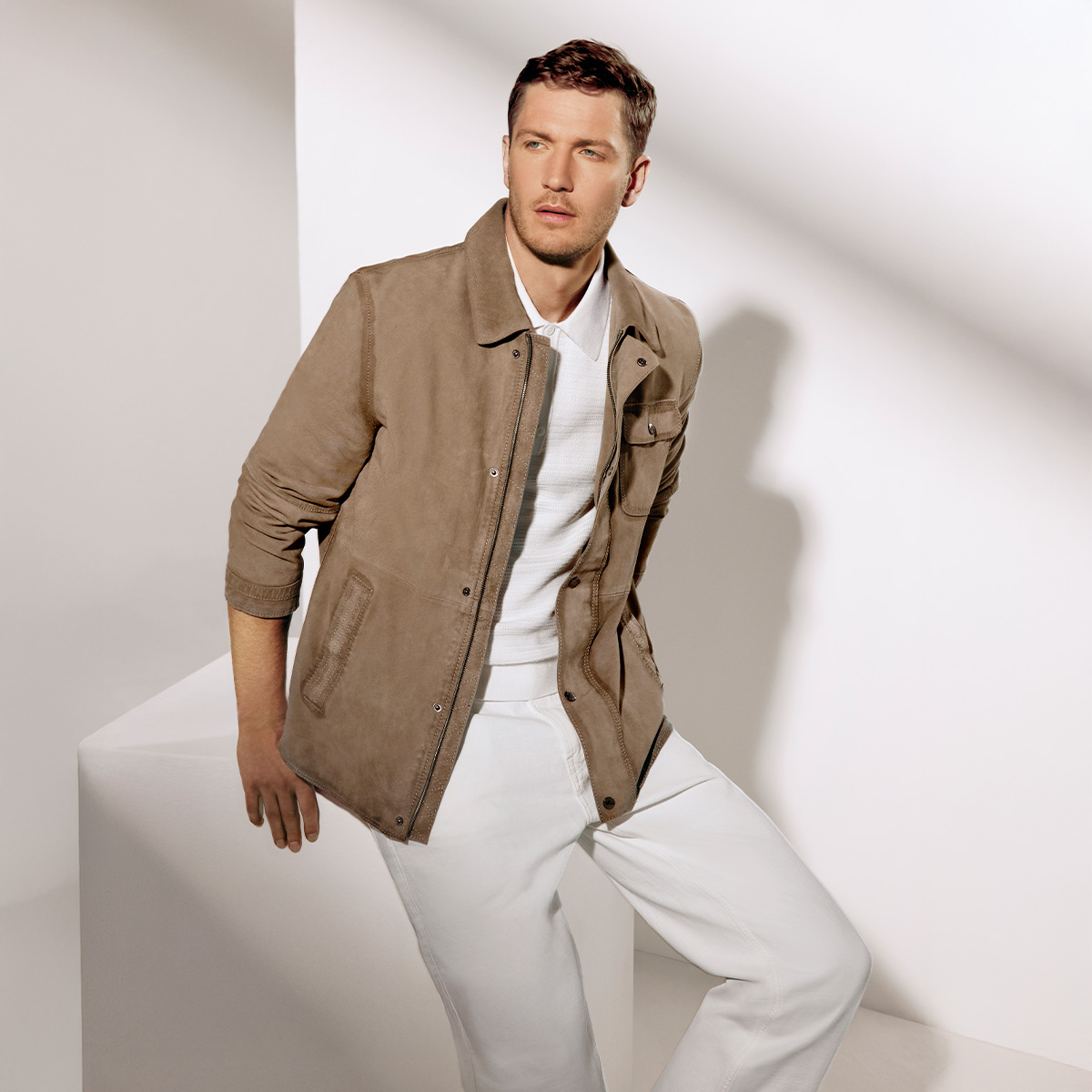 Mann in beigefarbener Wildlederjacke mit weißem Poloshirt, lässig getragen