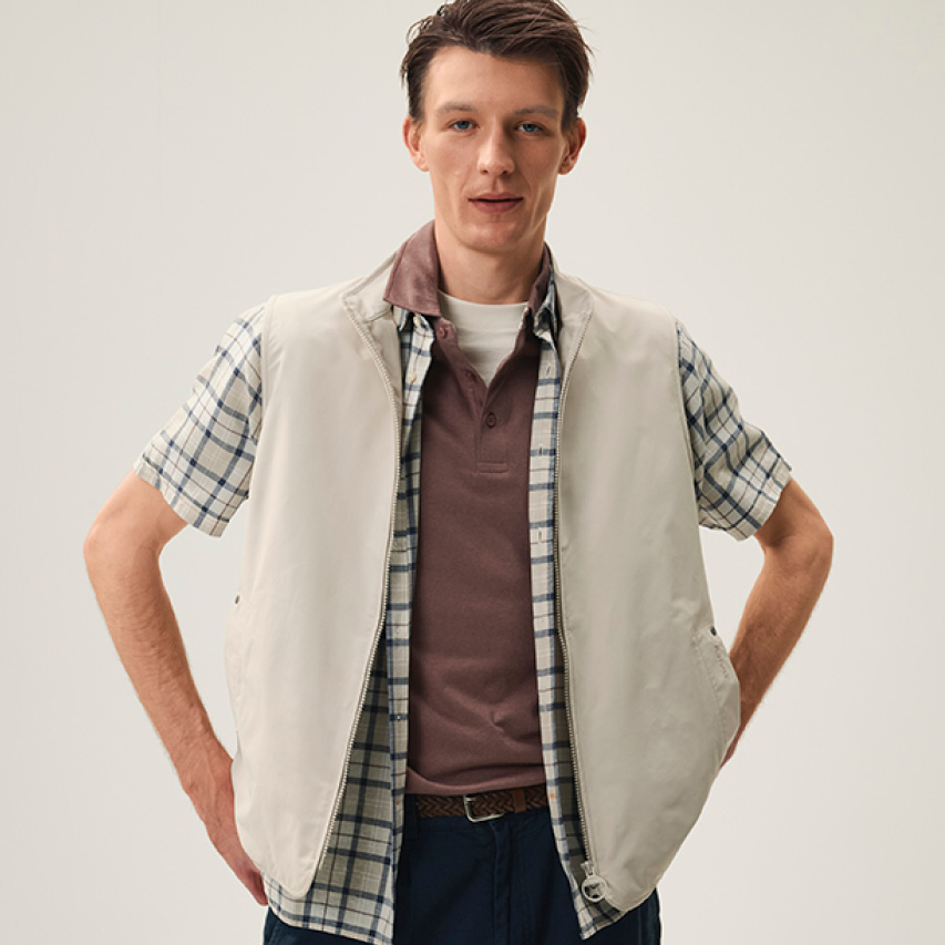 Herren-Weste in Beige mit kariertem Hemd und Poloshirt von Barbour, lässig getragen