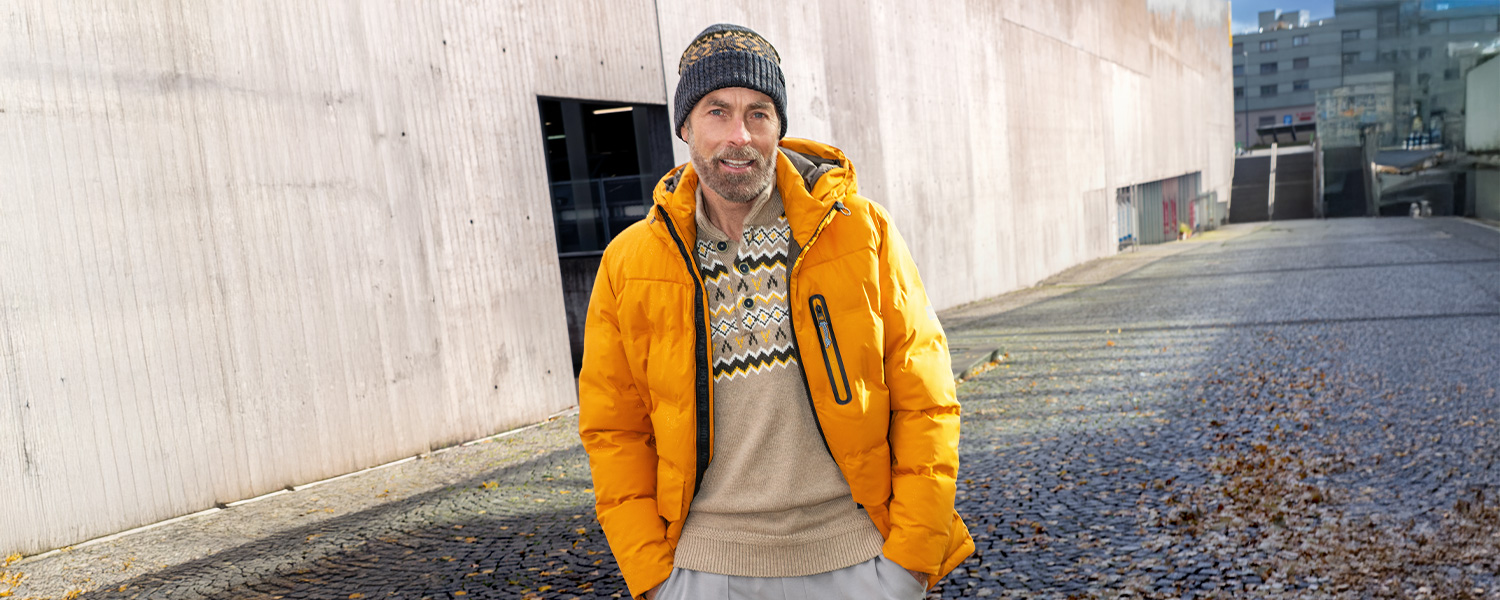 Man in gelber Daunenjacke über Norweger-Pullover, leger im Freien