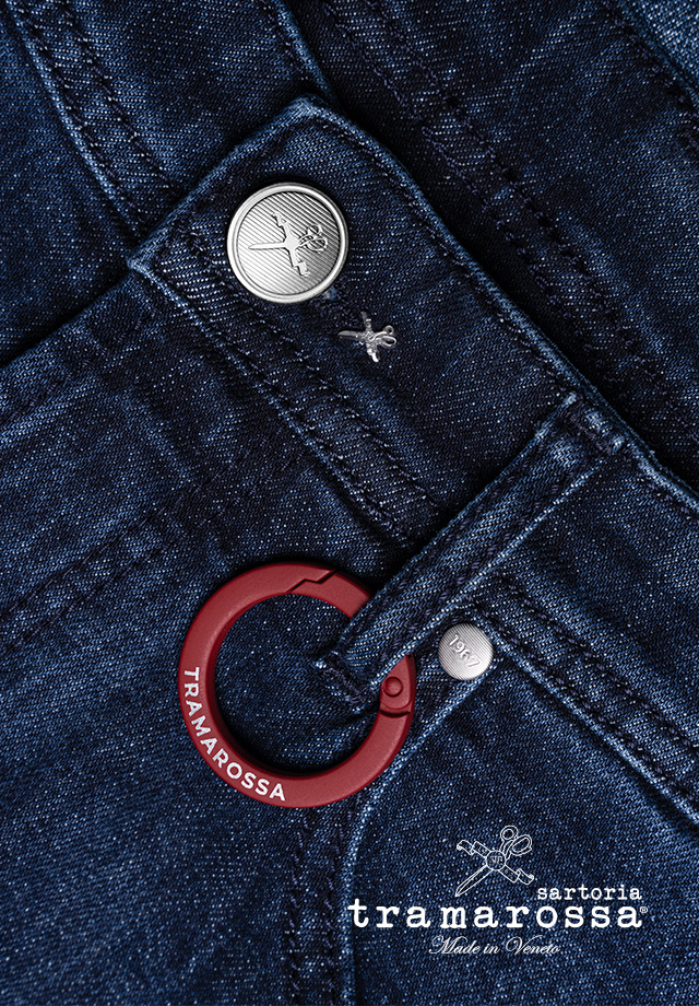 Marineblaue Jeans mit Silberknopf und rotem Anhänger, Detail-Aufnahme Hosentasche