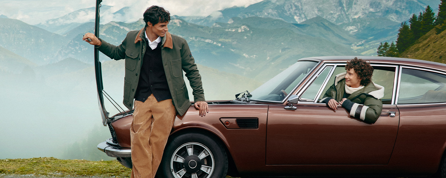 Mann in olivgrüner Fieldjacke mit Kordkragen und beiger Chino, Freizeitlook vor Bergkulisse