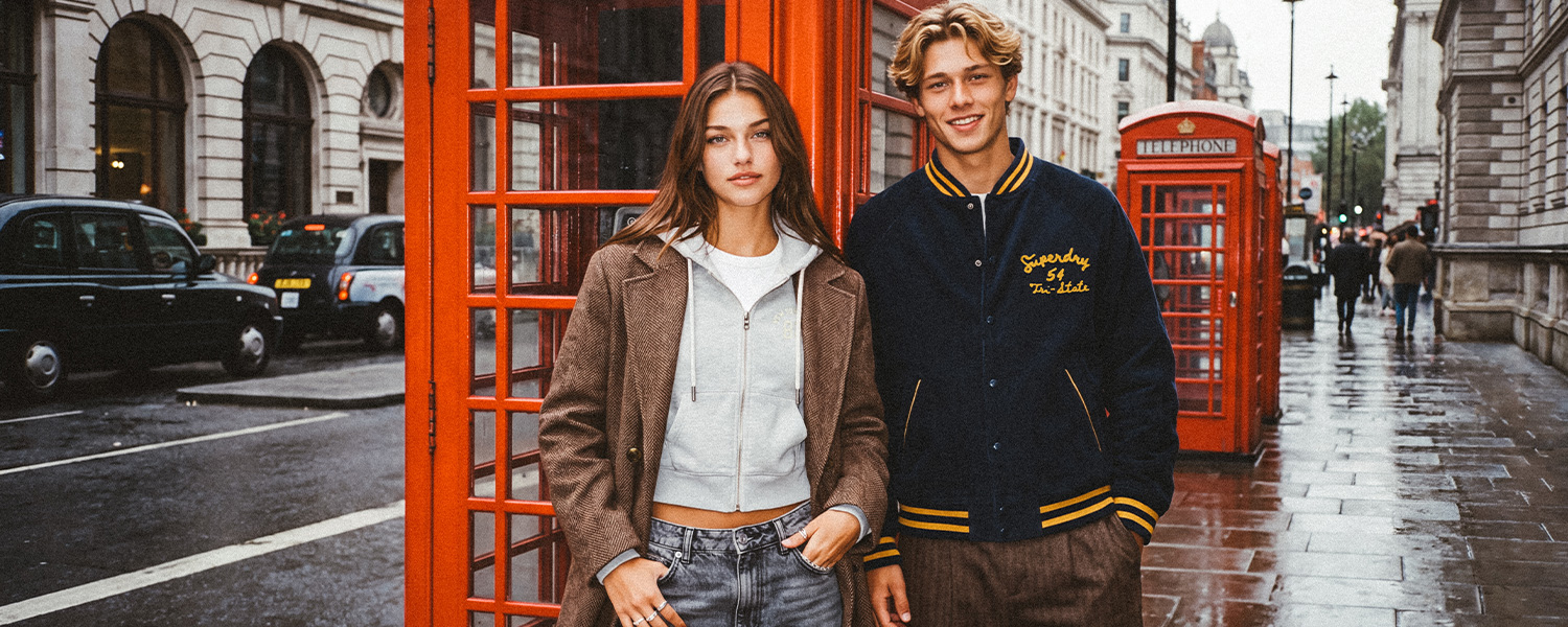 Mann in marineblauer College-Jacke mit gelben Streifen vor Londoner Telefonzelle