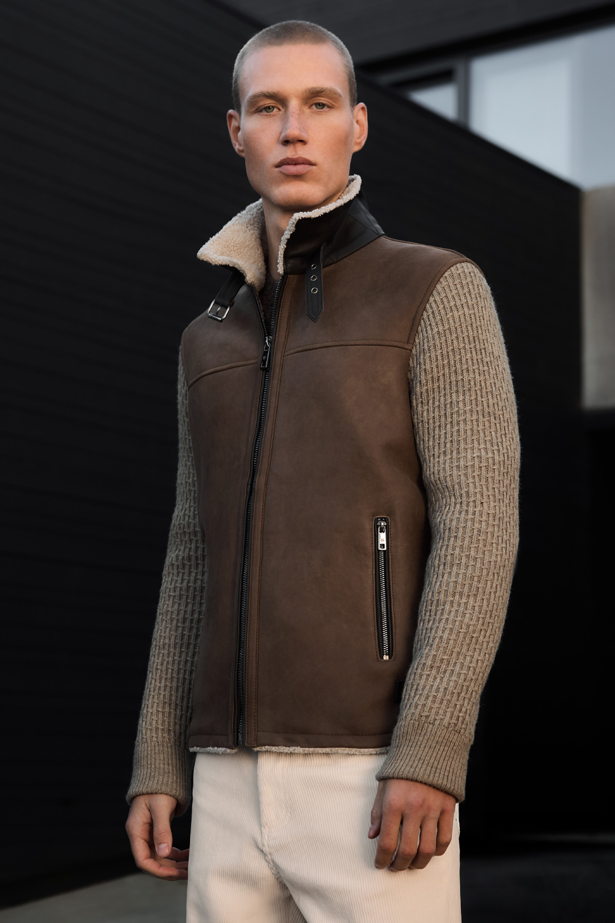 Mann in brauner Lammfellweste mit Strickärmeln in Beige, klassische Herbst-Wintermode