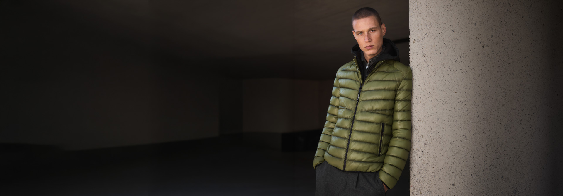 Mann in olivgrüner Steppjacke mit Kapuze und dunkler Hose, moderne Wintermode