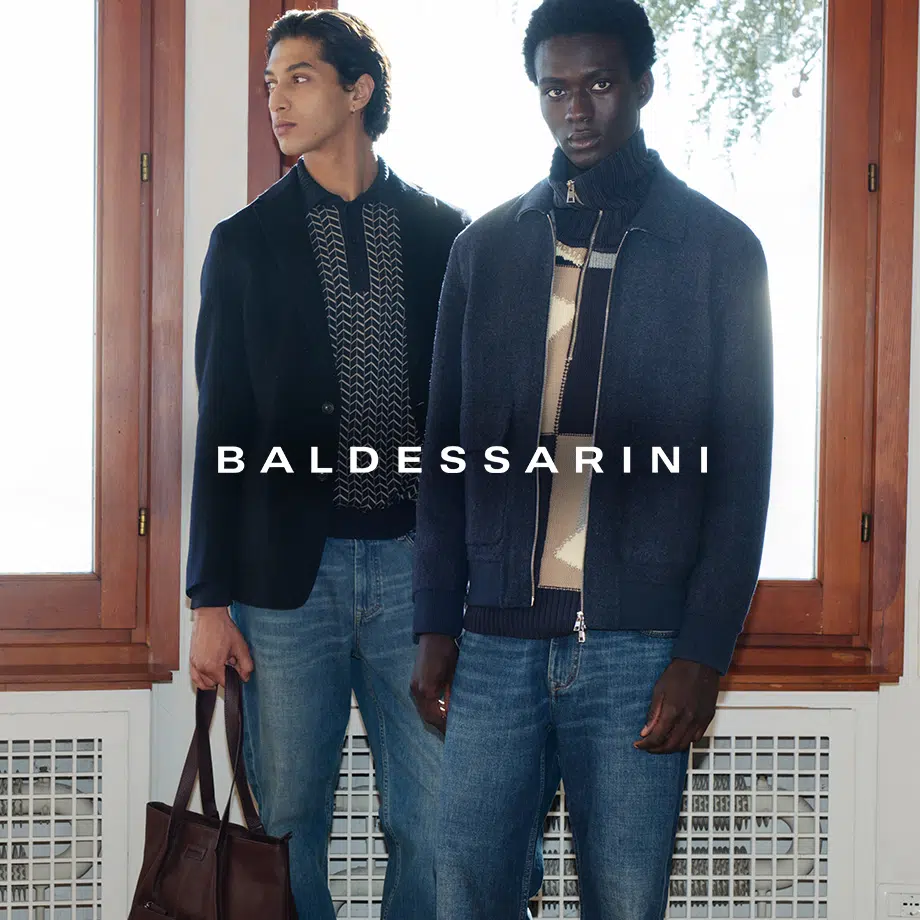 Zwei Männer in dunklen Wollmänteln und Strickpullovern, klassische Herbstmode am Fenster