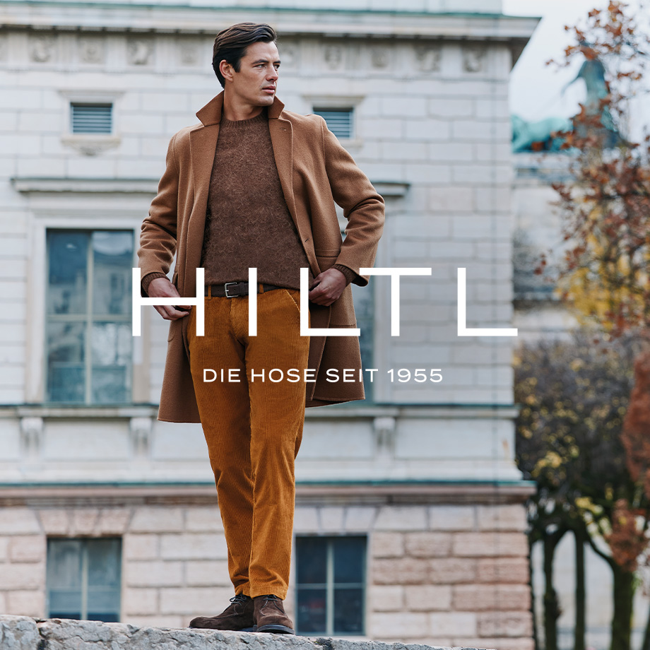 Mann in camelfarbenem Mantel, braunem Strickpullover und Cordhose im Herbst-Business-Casual-Outfit