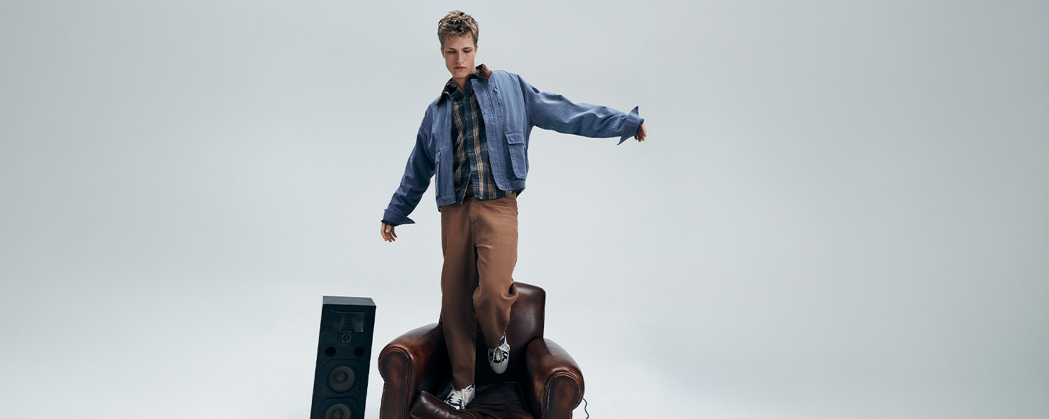 Mann in blauer Jeansjacke über kariertem Hemd mit brauner Chino-Hose, lässige Freizeitmode