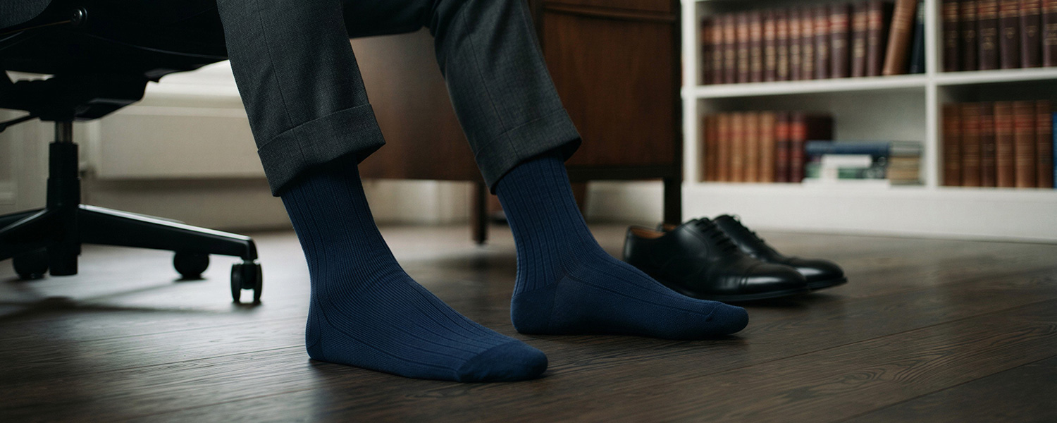 Marineblaue Business-Socken mit Rippenstruktur zu grauer Anzughose, getragen im Büro
