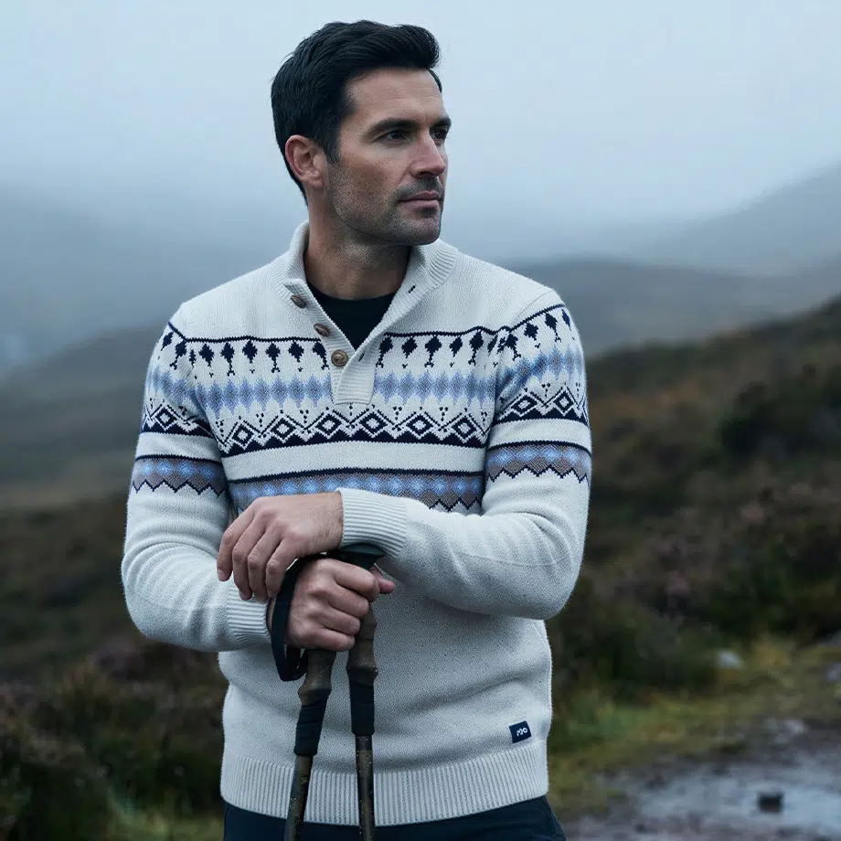 Mann in hellgrauem Strickpullover mit nordischem Muster in Blau und Schwarz, Schalkragen mit Knopf