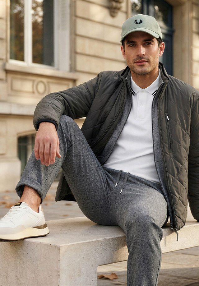 Mann in olivgrüner Steppjacke mit grauer Jogginghose und weißem Poloshirt, Freizeitlook mit Baseball-Cap