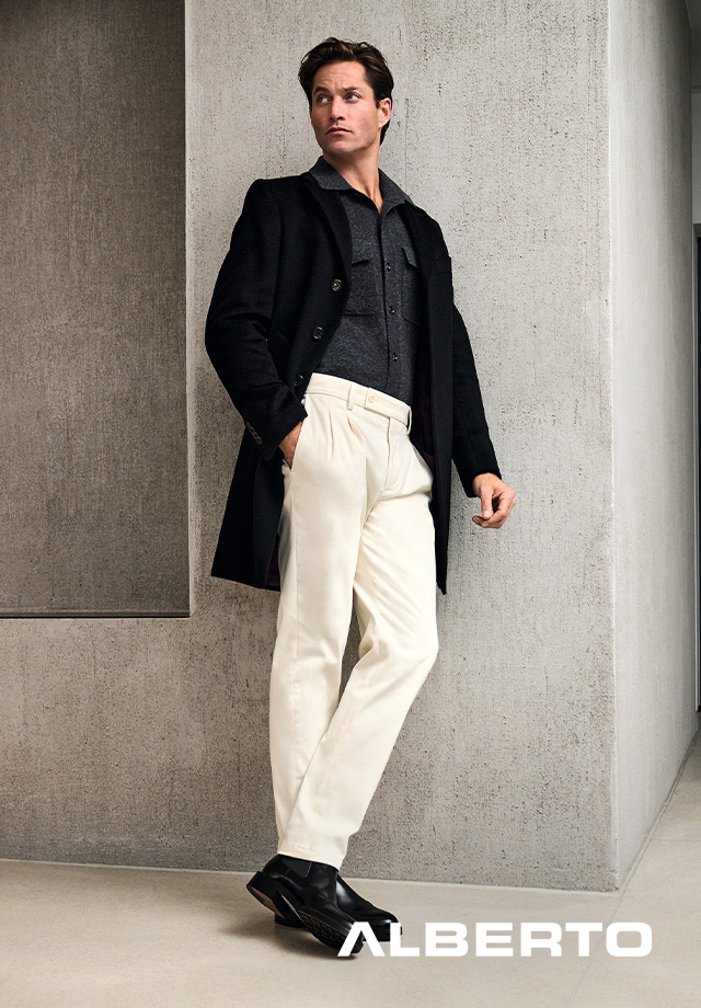 Mann in schwarzem Wollmantel, dunkelgrauem Poloshirt und cremefarbener Bundfalten-Hose, Business-Casual-Outfit