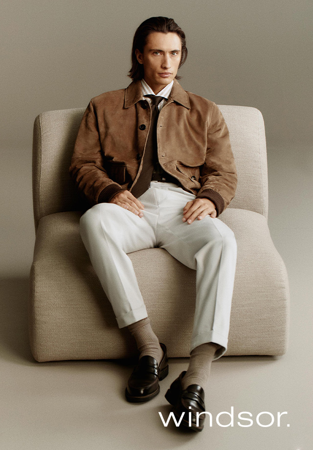 Mann in beiger Wildlederjacke und weißer Chino, elegant sitzend im Business-Casual-Look