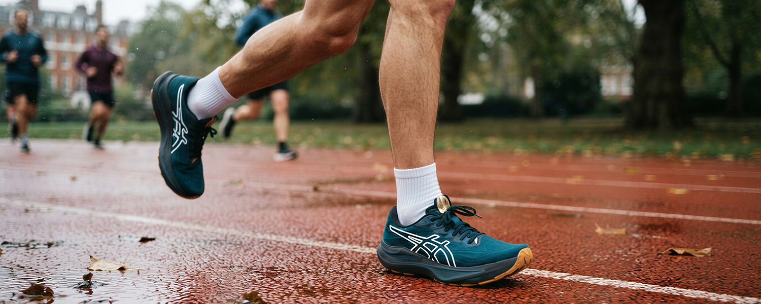 Mann in weißen Sportsocken beim Laufen auf Tartanbahn im Park