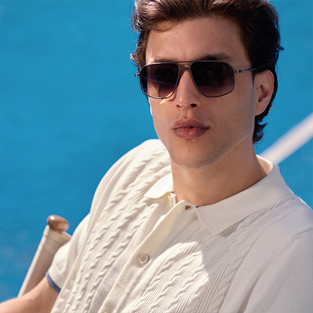 Weißes Strickpoloshirt mit Zopfmuster, getragen von Mann mit Sonnenbrille am Pool