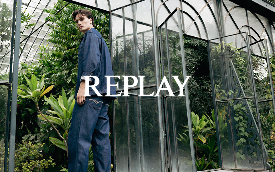 Mann in dunkelblauer Jeansjacke und Jeans vor Glashaus, legerer Look