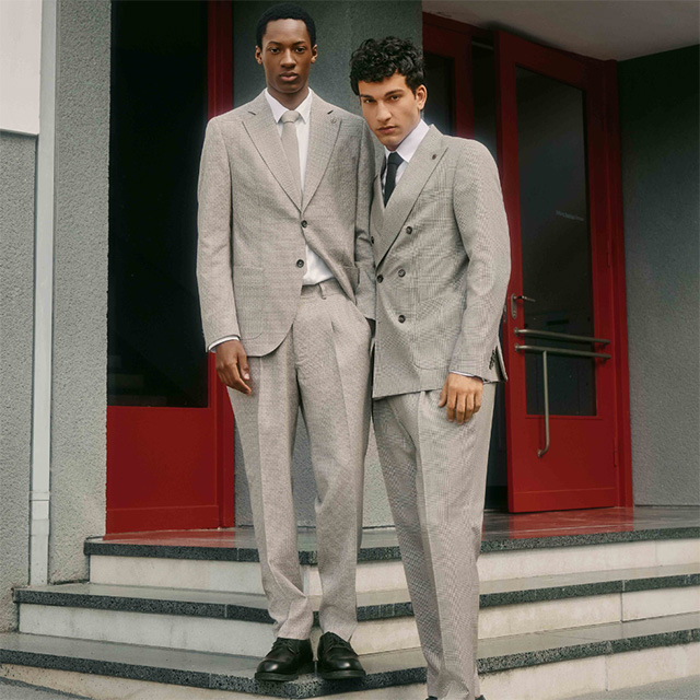 Herren in grauen Anzügen mit feinem Karo-Muster, einreihig und doppelreihig, vor roter Tür